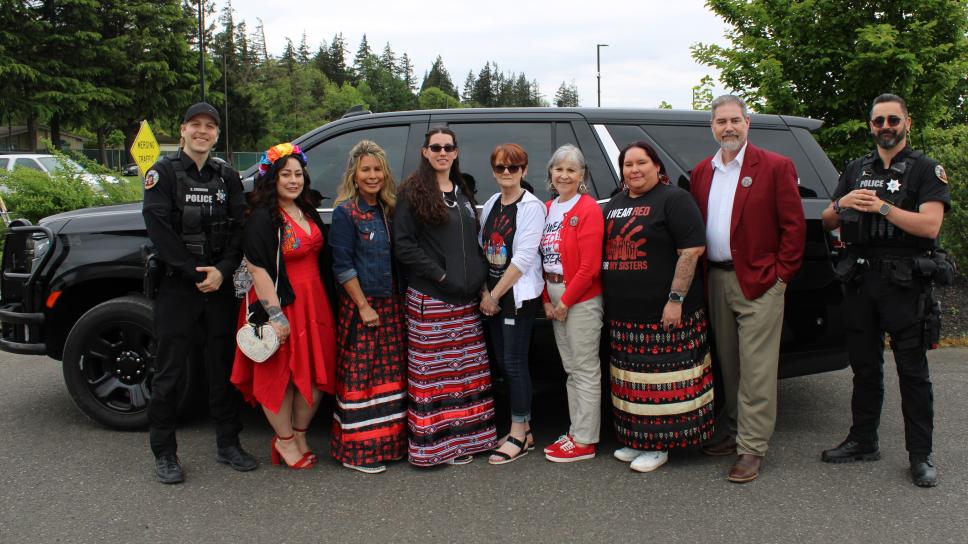 Cowlitz Tribal Public Safety and Pathways To Healing and Health and Human Services employees stand in front of the Public Safety vehicle wearing red. 